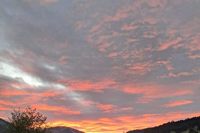 Blick von einer Brücke auf den Fluss im Tannheimer Tal, Tirol, bei Abendrot.