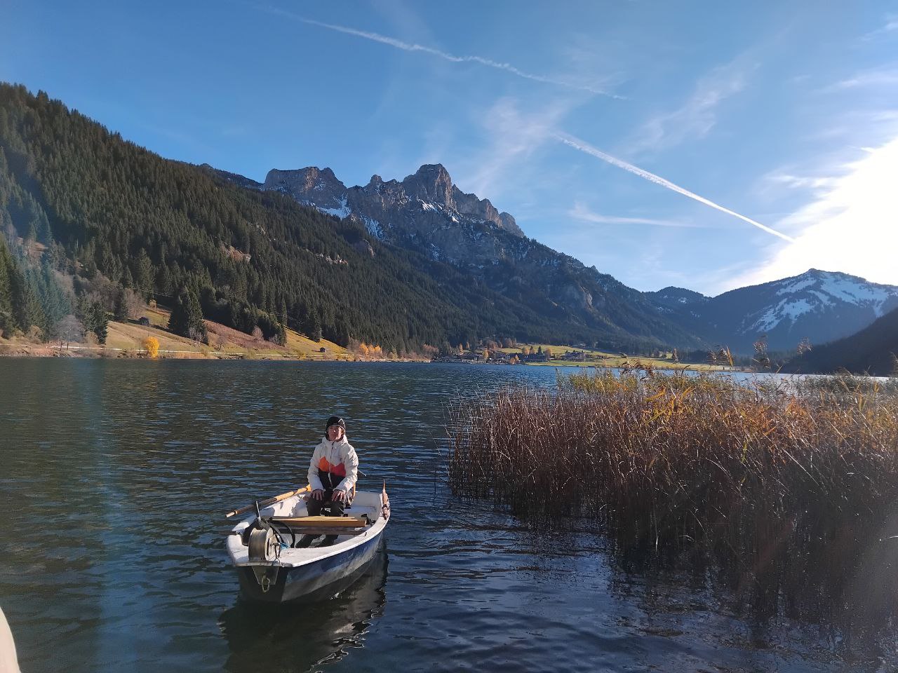 Angelboot auf einem See im Tannheimer Tal, Tirol, mit Bergpanorama und blauem Himmel im Hintergrund.